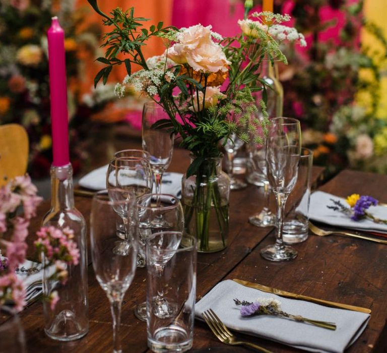 Industrial wedding reception in London with lots of bright floral decor and tall candlesticks