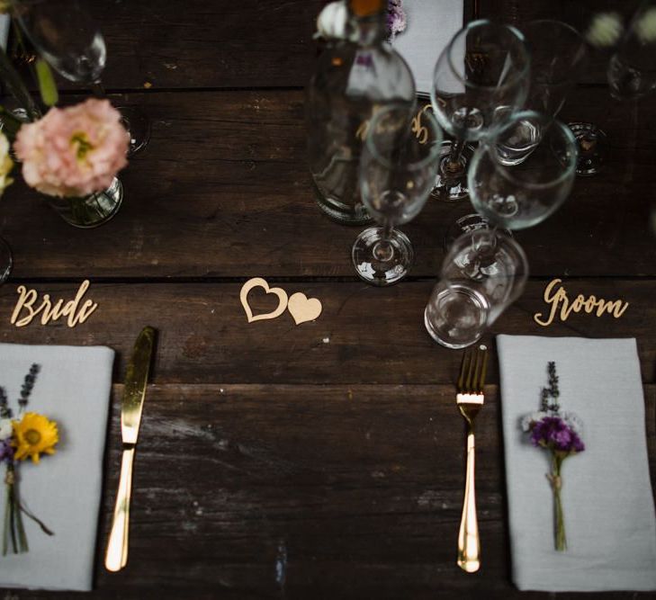 Bride and groom place settings at industrial styled wedding reception with hand tied floral decor