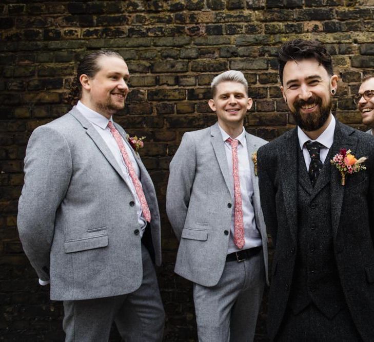 Groom and his groomsmen at industrial wedding in London with bright floral buttonhole and three-piece suit