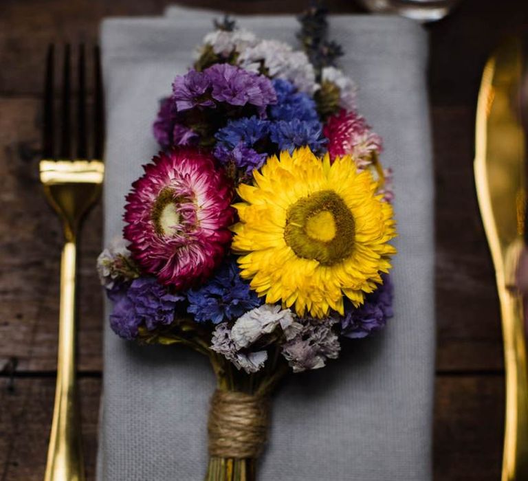 Bright floral table arrangements and gold cutlery at industrial wedding in London