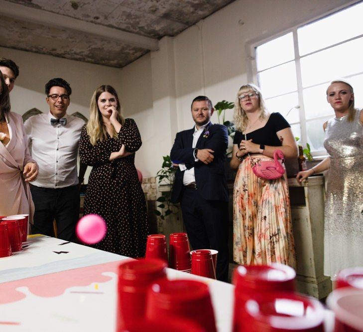 Guests enjoying beer pong at industrial wedding with casual floral decor