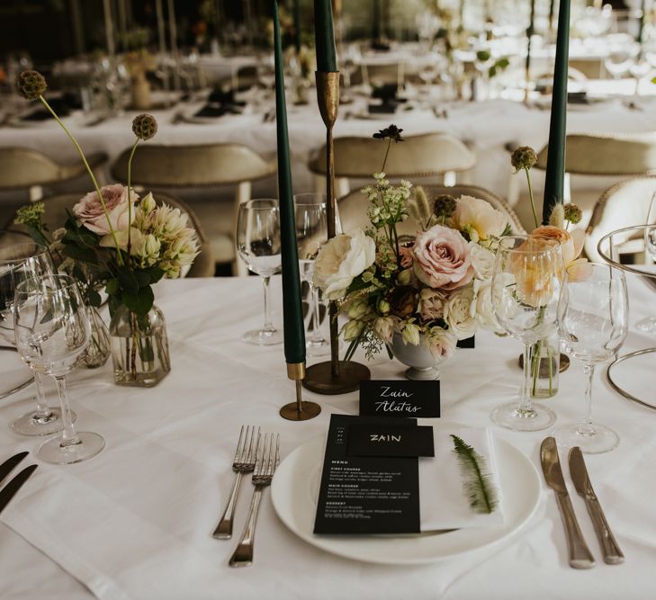 Elegant place setting with green taper candles, floral centrepiece and menu card