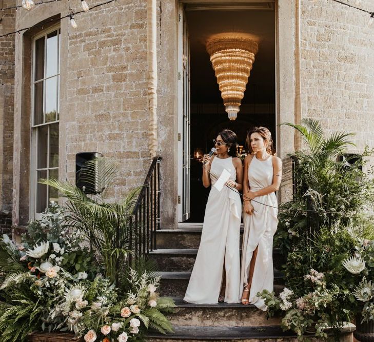 Bridesmaids in white dresses giving speeches outside at Babington House wedding venue