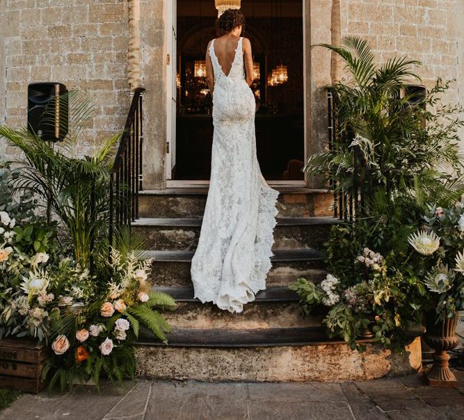 Bride in Pronovias wedding dress walking up the flower decorated steps at Babington House wedding venue