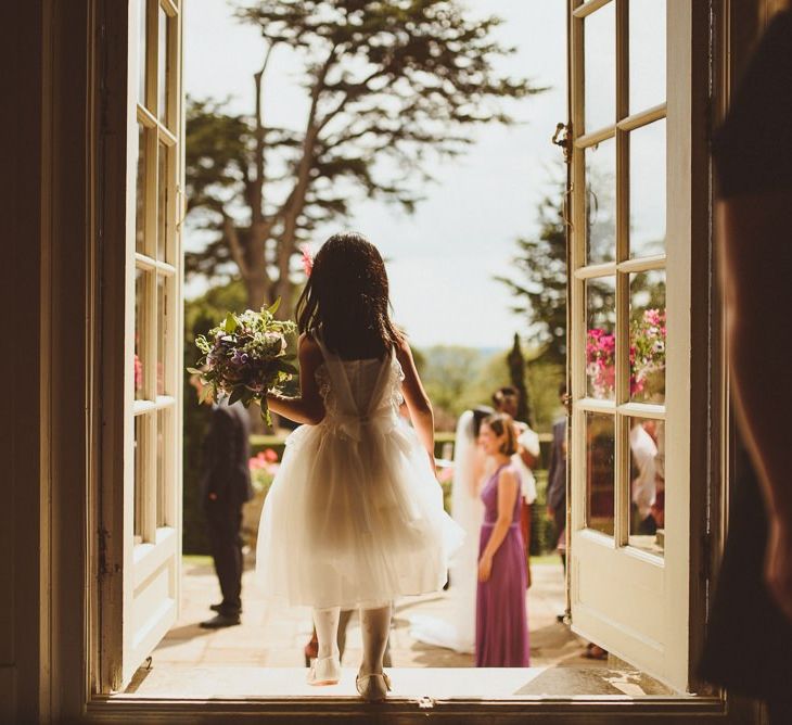 Flower girl in white dress standing in a doorway