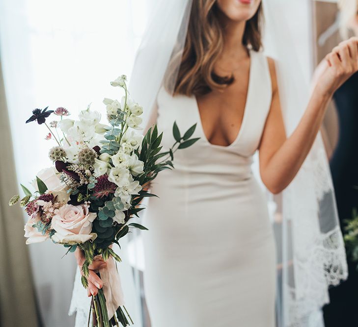 Bride wearing timeless dress with long lace tipped veil and  black bridesmaid dresses