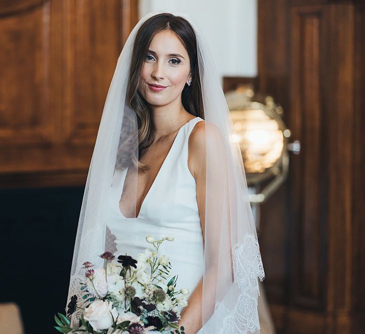 Bride in timeless dress with autumnal bouquet and black bridesmaid dresses