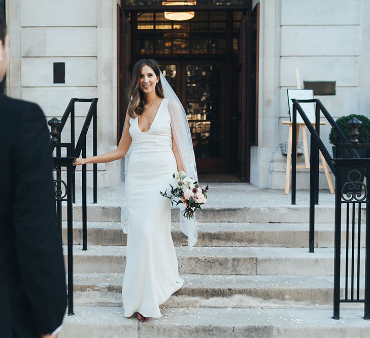 Bride in elegant dress with veil and dusky pink  wedding bouquet