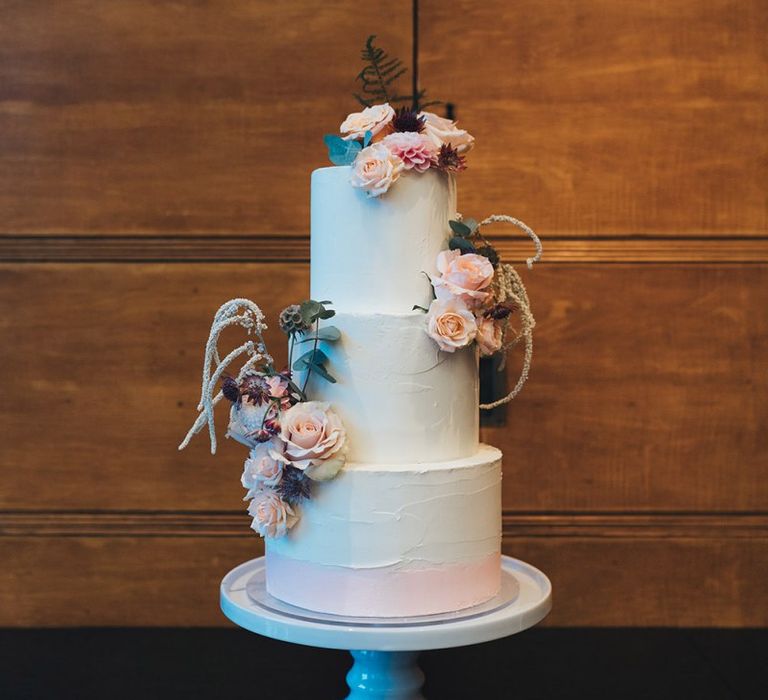 Buttercream wedding cake with dusky pink floral decoration at city wedding reception