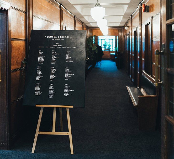 Black and white peg board seating plan at Town Hall wedding in East London with black bridesmaid dresses