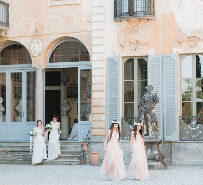 Bridesmaids in Peach Dresses and Flower Crowns Walking Along the Courtyard