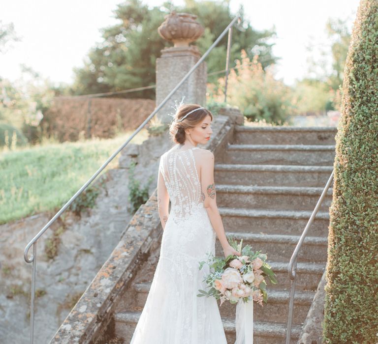 Bride in Lace Atelier Eme Wedding Dress with Ornate Headdress and Romantic Bouquet