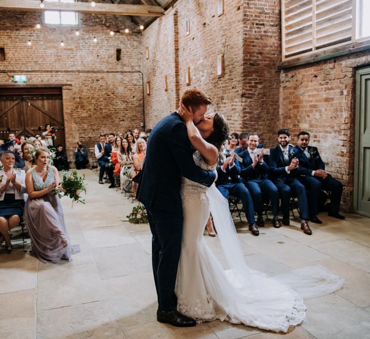 Bride in Lace Roland Joyce Bridal Wedding Dress and Groom in Navy Suit Embracing During Wedding Ceremony