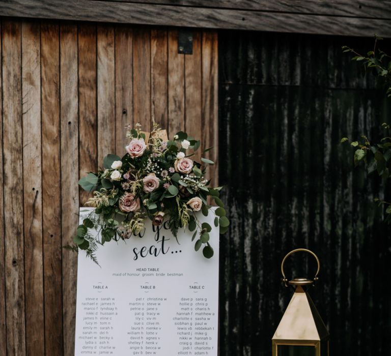 Calligraphy Seating Chart on Wooden Easel Decorated with Pink Flowers