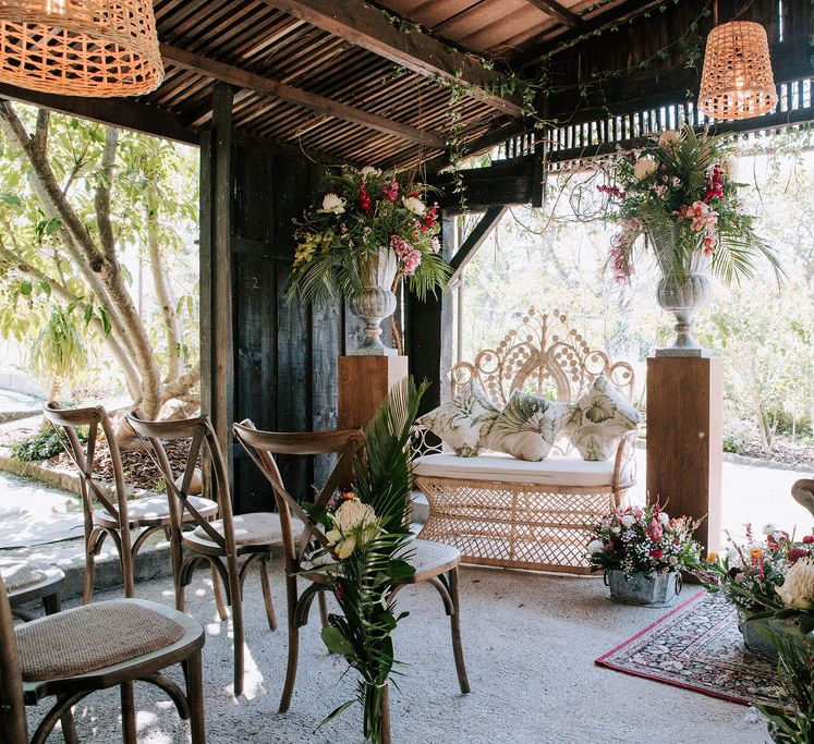 wooden ‘pagoda’ wedding ceremony with wicker lamps and chairs and botanical plant decor