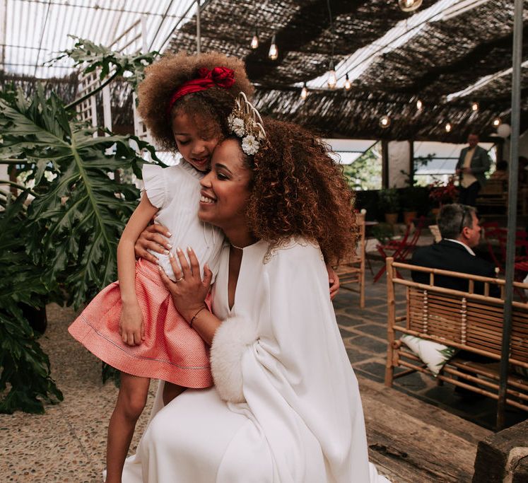 Bride with Afro Hair in Gold Headdress, Patricia Meléndez Wedding Dress and coat Hugging Little Girl