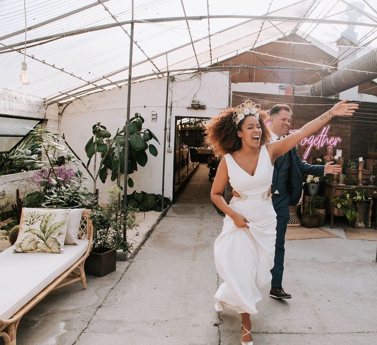 Bride with Afro Hair in Gold Headdress and Patricia Meléndez Wedding Dress and Groom in Navy Suit Enterting Glasshouse Wedding Venue