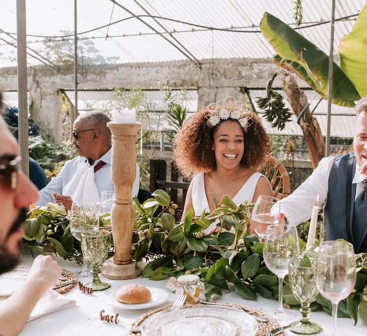 Bride with Afro Hair in Gold Headdress and Patricia Meléndez Wedding Dress and Groom in Navy Suit Enjoying Botanical Wedding Reception