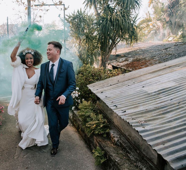 Bride with Afro Hair in Gold Headdress, Patricia Meléndez Wedding Dress and coat and Groom in Navy Suit Waving Coloured Flares