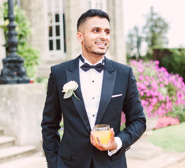 Stylish Groom in a Black Tie Suit with Bow Tie and White Flower Buttonhole