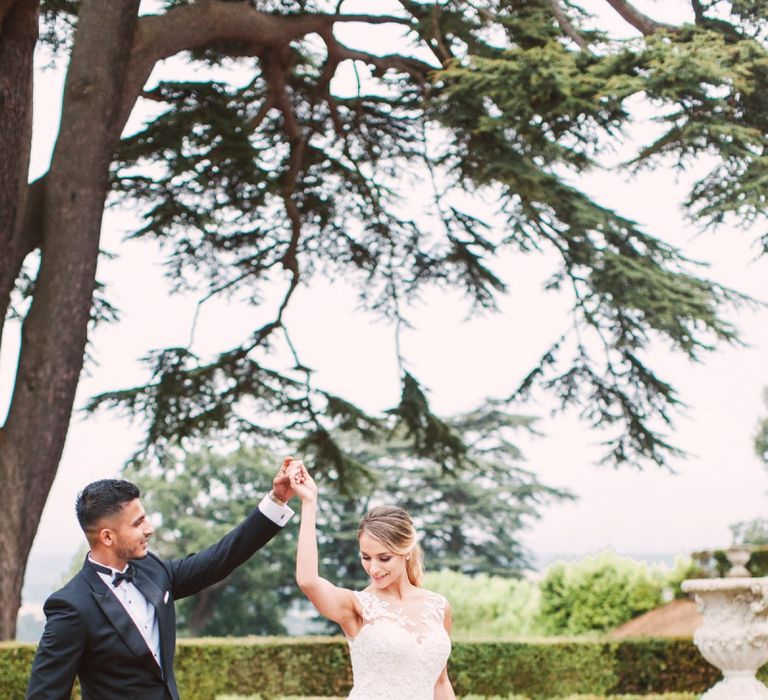 Groom in Black Tie Suit Twirling his Bride in her Lace Pronovias Wedding Dress