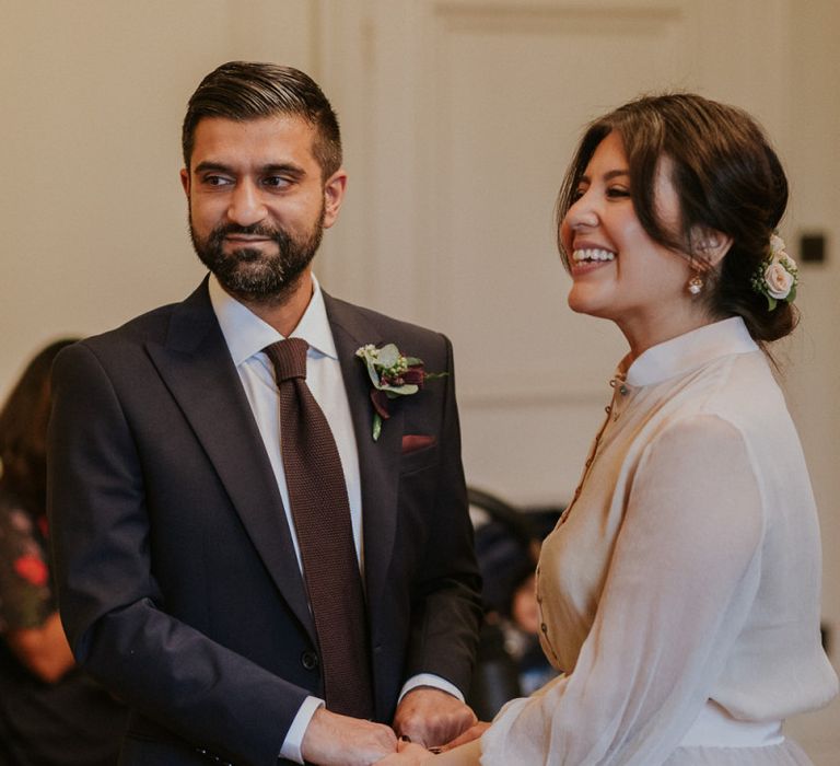 Bride and groom holding hands during town hall wedding reception