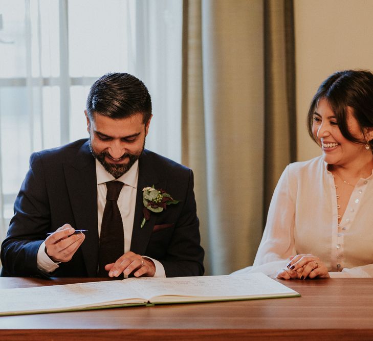 Bride and groom signing the register at intimate town hall wedding