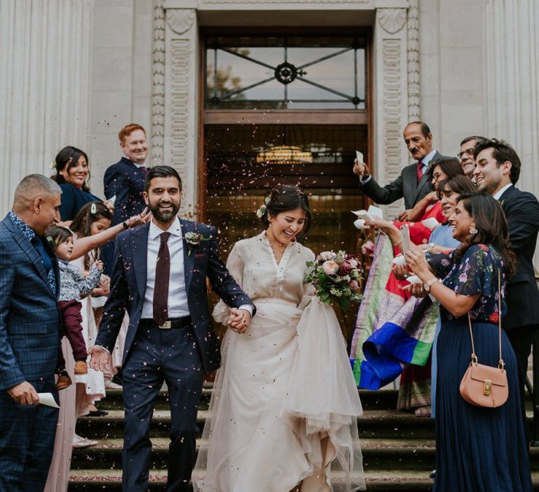 Bride in tulle skirt separates and groom in navy suit at town hall wedding