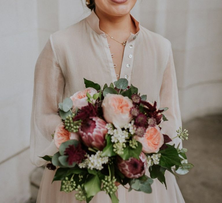 Bride holding a david austin rose and protea wedding bouquet