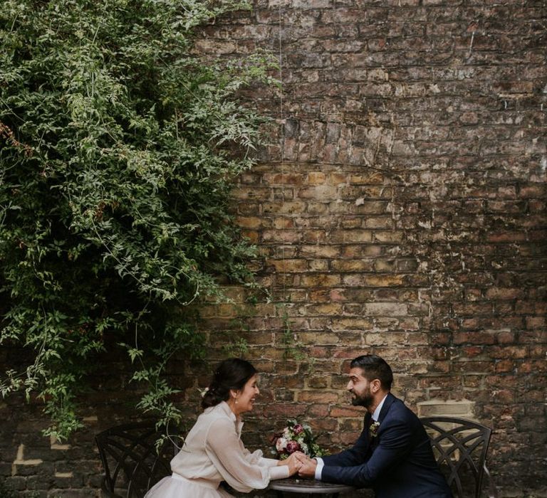 Bride and groom portrait sitting at a table with bride in tulle skirt