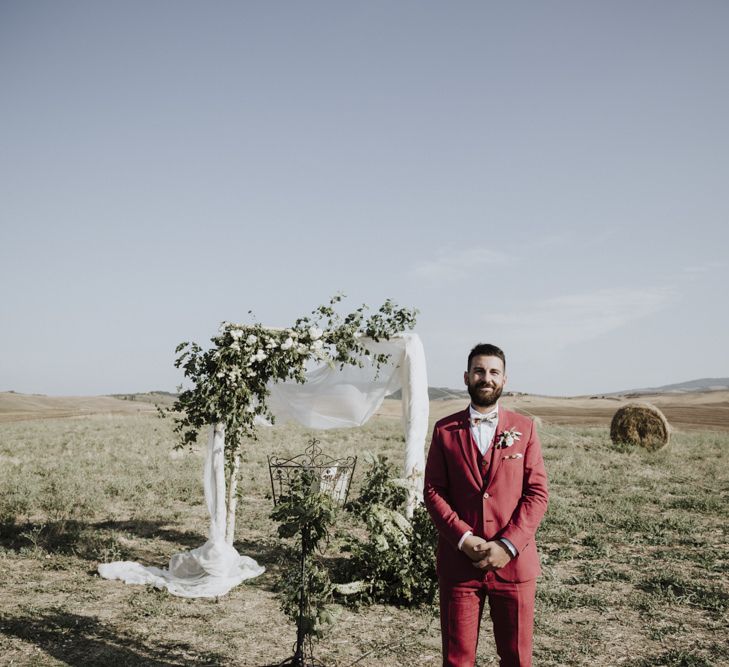 Groom in red suit waits at altar for bride