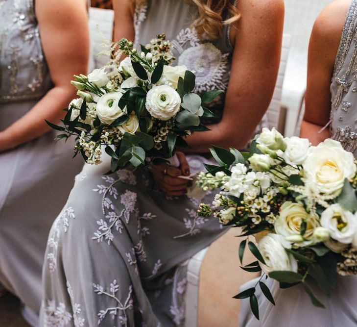 Bridesmaids wearing soft grey dresses and white floral bouquets