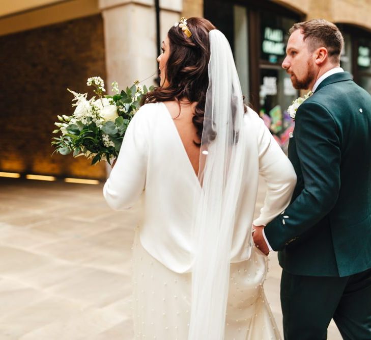 Back of brides two piece dress with softly curled hair and veil