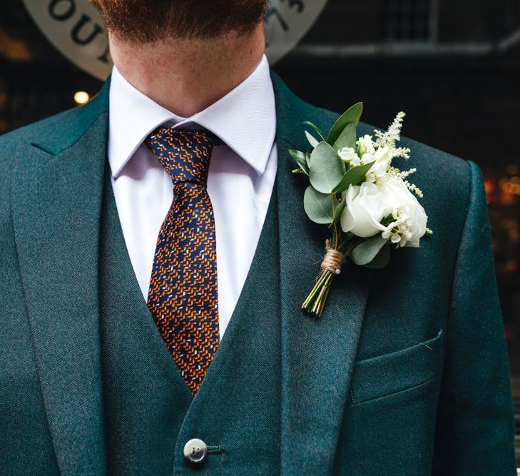 Groom wearing three piece suit with white floral buttonhole