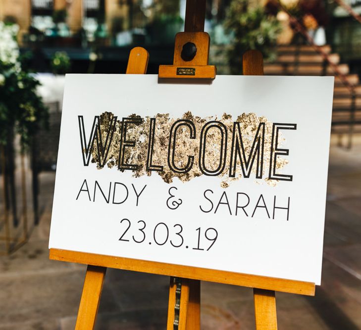 Black and white wedding sign at courtyard ceremony with gold foiling