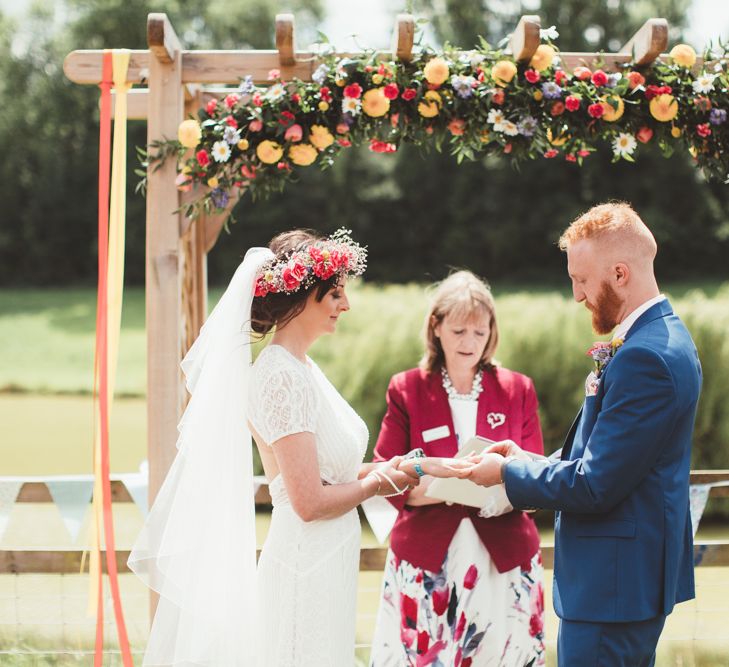 Wedding Ceremony | Bride in Lace Watters Gown &amp; Colourful Flower Crown | Groom in Navy Suit | Bright Festival Themed Outdoor Ceremony &amp; Tipi Weeding |  Maryanne Weddings | Framed Beauty Film