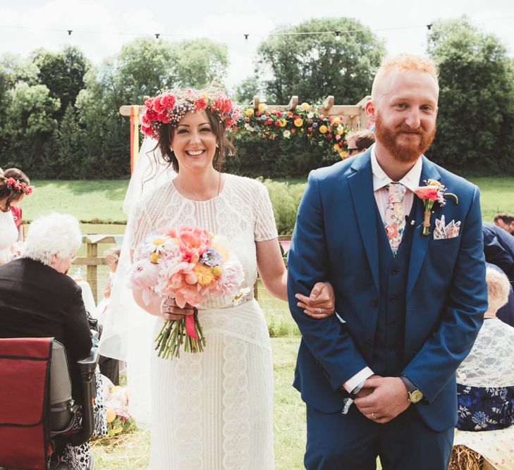 Bride in Lace Watters Gown &amp; Colourful Flower Crown | Groom in Navy Suit | Bright Festival Themed Outdoor Ceremony &amp; Tipi Weeding |  Maryanne Weddings | Framed Beauty Film