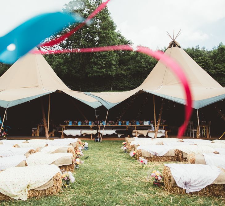 Hay Bale Ceremony Seating | Bride in Lace Watters Gown &amp; Colourful Flower Crown | Groom in Navy Suit | Bright Festival Themed Outdoor Ceremony &amp; Tipi Weeding |  Maryanne Weddings | Framed Beauty Film