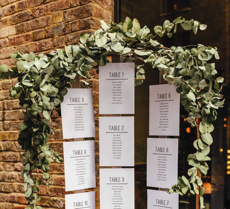 Hanging table plan with foliage decor and candle lanterns