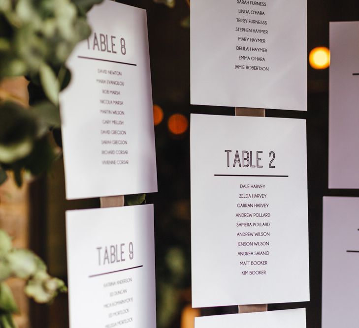 Hanging table plan with foliage decor and candle lanterns