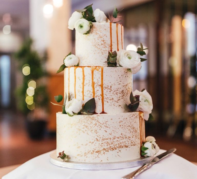 Three tier wedding cake with gold decoration and white florals