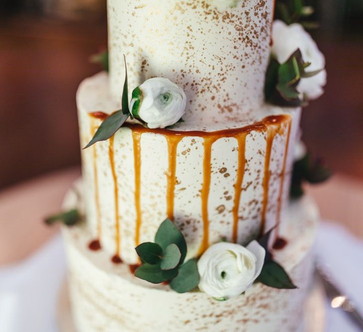 Three tier wedding cake with gold decoration and white florals