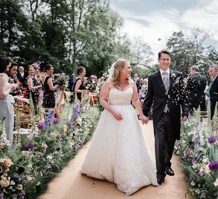 Bride in Lace Sophia Tolli Wedding Dress and Groom in Traditional Tails Walking up the Aisle as Husband and Wife