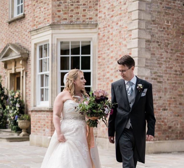 Bride in Lace Sophia Tolli Wedding Dress and Groom in Traditional Tails Walking Together