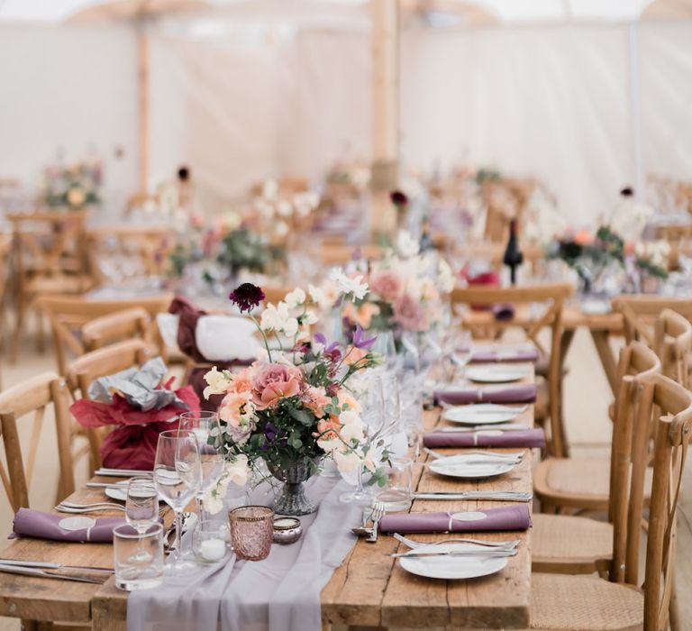 Marquee Wedding Reception Decor with Wooden Tables and Floral Centrepieces