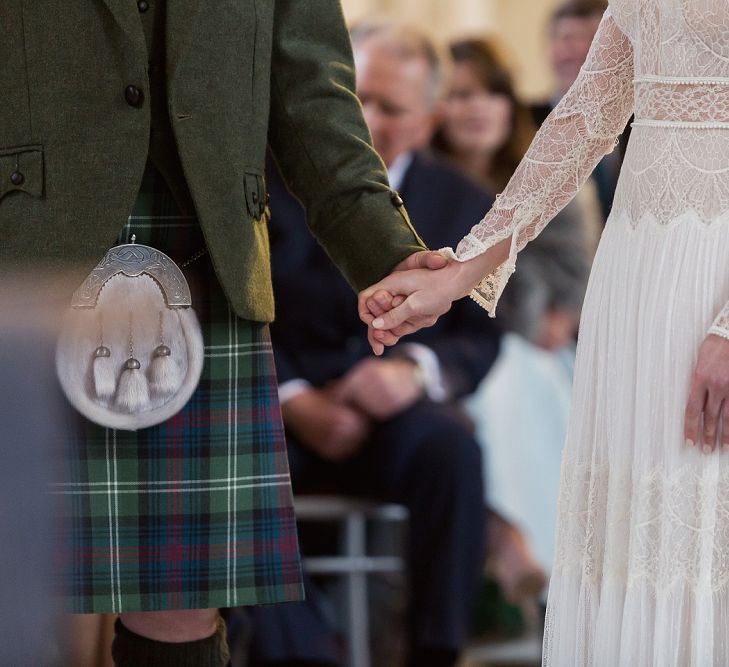 Wedding Ceremony with Bride in Delicate Lace Lihi Hod Sophia Wedding Dress with Long Sleeves and Groom in Traditional Tartan Kilt Holding Hands at the Altar