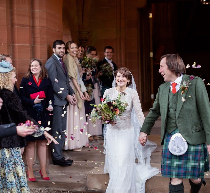 Confetti Moment with Bride in Delicate Lace Lihi Hod Sophia Wedding Dress with Long Sleeves and Groom in Traditional Tartan Kilt