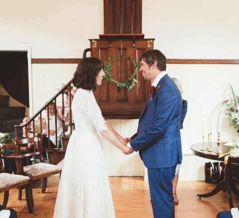 Bride in Lace Wedding Dress from Hope &amp; Harlequin and Groom in Navy Hugo Boss Suit at the Altar