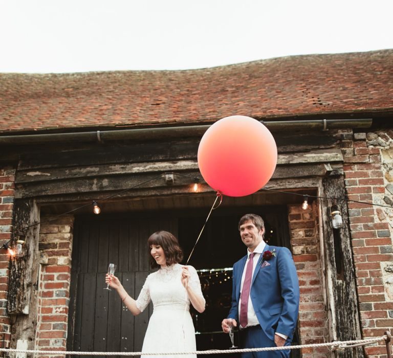 Bride in Lace Wedding Dress from Hope &amp; Harlequin and Groom in Navy Hugo Boss Suit  Entering Drinks Reception with Giant Balloon