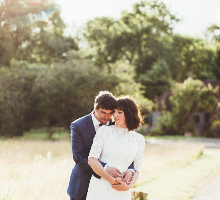 Bride in Lace Wedding Dress from Hope &amp; Harlequin and Groom in Navy Hugo Boss Suit Embracing